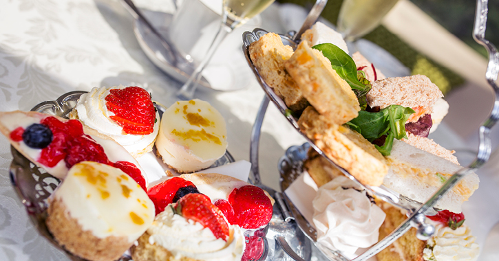 selection of cakes and sandwiches on a table with white tablecloth, part of an afternoon tea